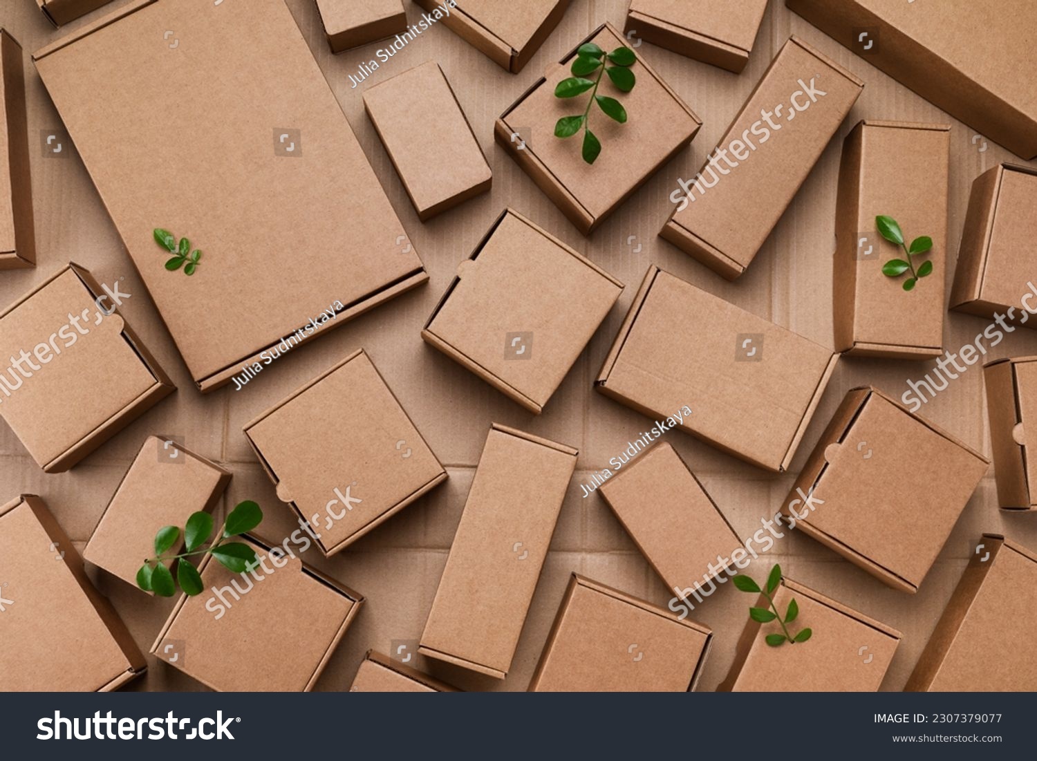 Heap of cardboard boxes from natural recyclable materials with green leaves sprout top view. Responsible consumption, eco friendly packaging, zero waste concept. #2307379077