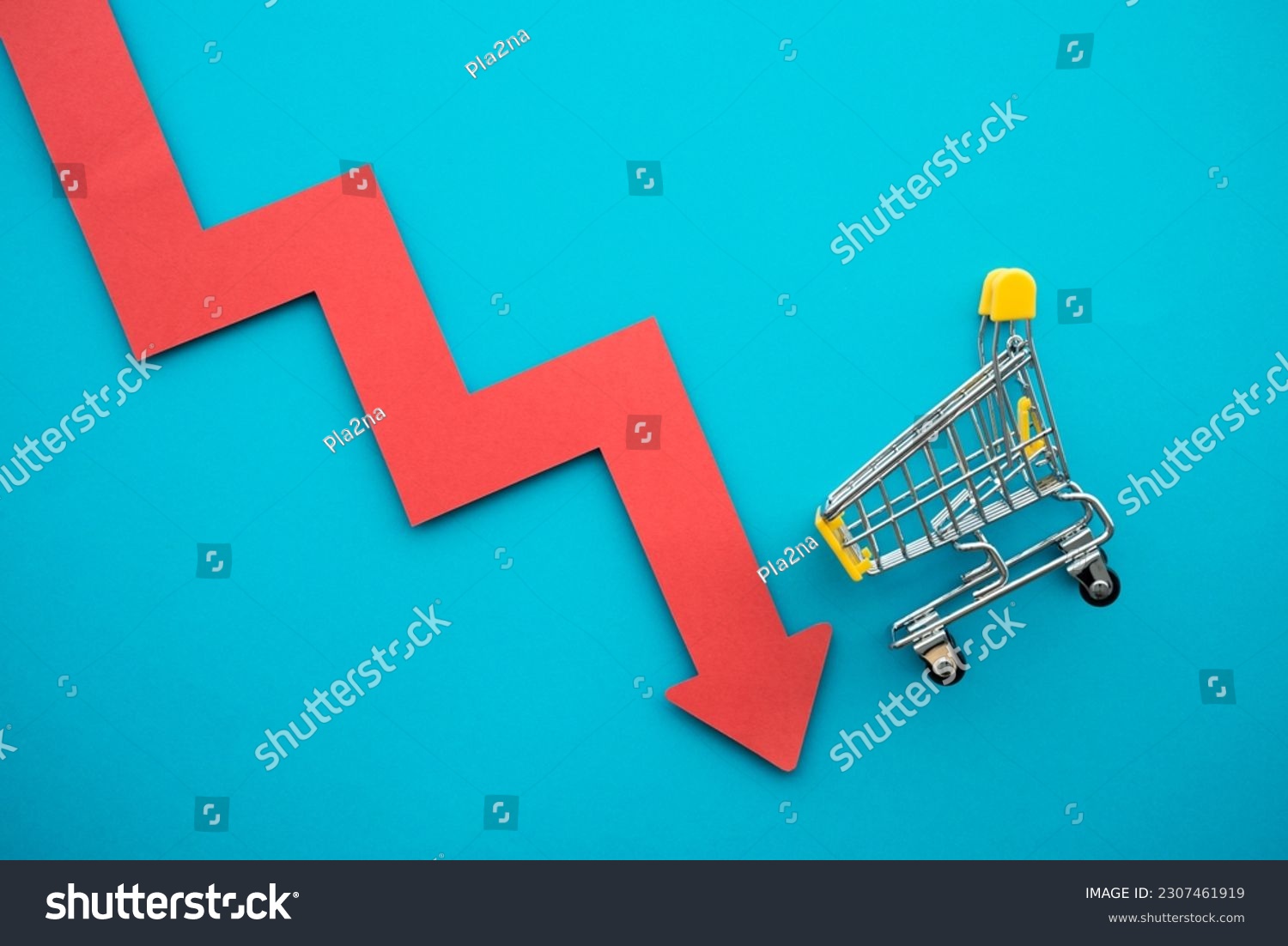 Shopping trolley with red chart falling down on blue background copy space. Global economic recession crisis, core retail sales decrease, inflation or goods price up concept. #2307461919