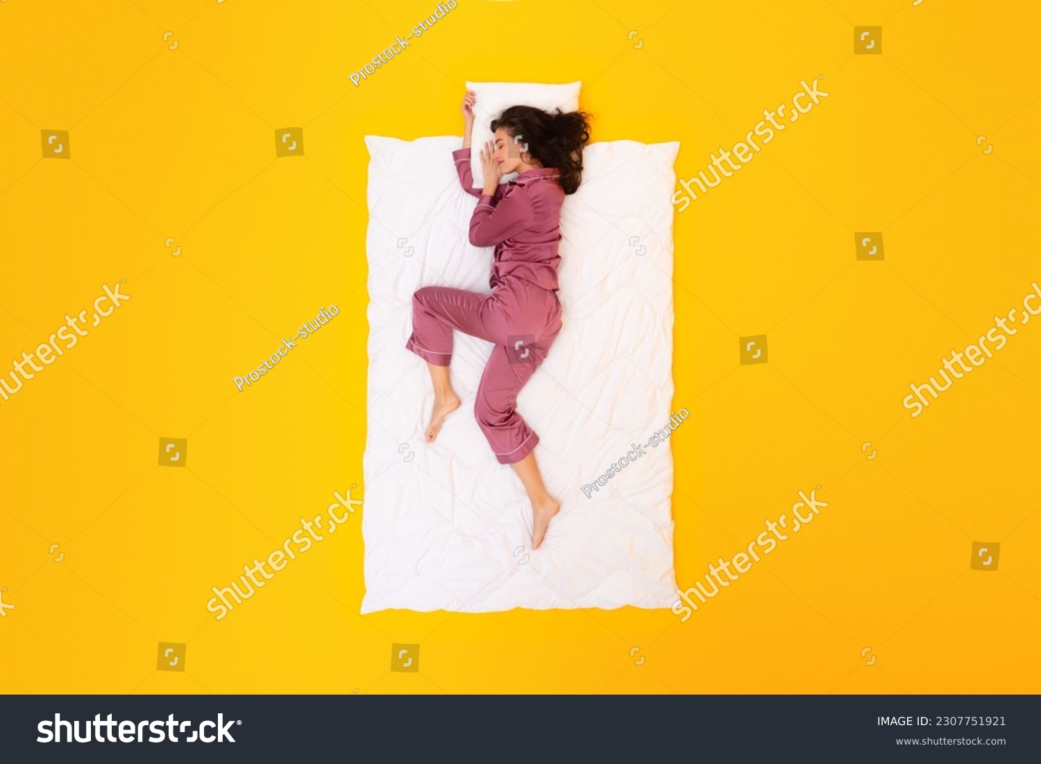 Dreamy Nights. Peaceful Lady In Pajamas Sleepwear Drifting in Sleep Lying On Blanket Hugging Pillow On Yellow Studio Background, Above View Shot. Restful Beauty Sleep Concept #2307751921