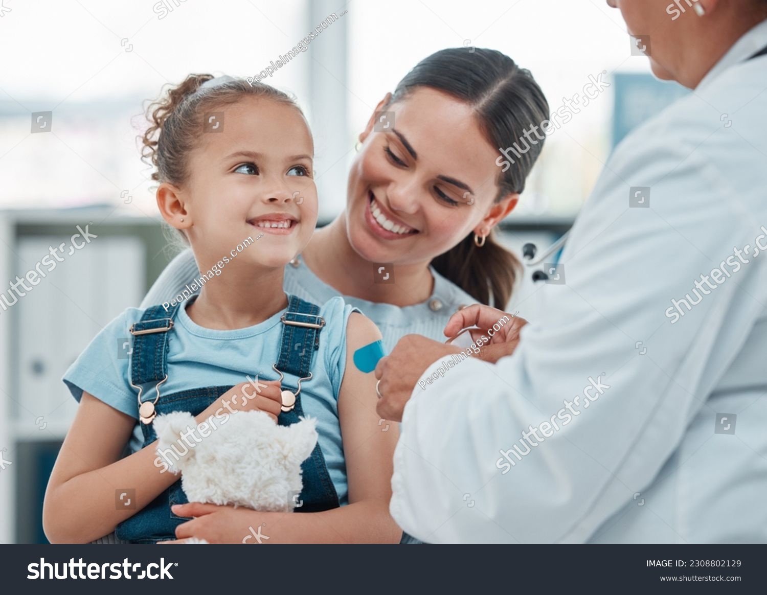 Girl, mom and doctor with vaccine injection, cotton ball and flu shot on arm for disease or covid prevention in hospital. Woman, nurse and child with pediatrician help with bandaid, teddy or health #2308802129