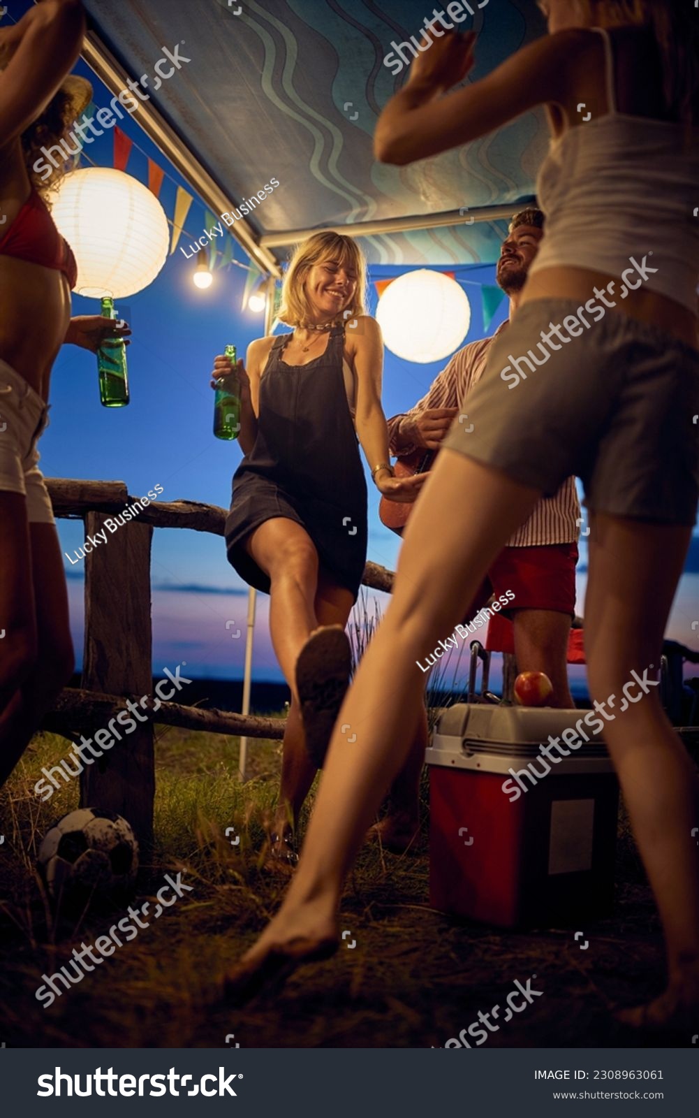 Young people celebrating, dancing and having fun outdoors in camp. Summertime sunset. Travel, weekend, togetherness, lifestyle concept. #2308963061