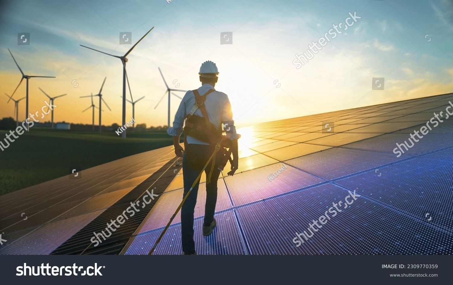 Professional Male Green Energy Engineer Walking On Solar Panel, Wearing Safety Belt And Hard Hat. Man Inspecting Sustainable Energy Farm With Wind Turbines. VFX Edit Visualizing Electricity Flow. #2309770359