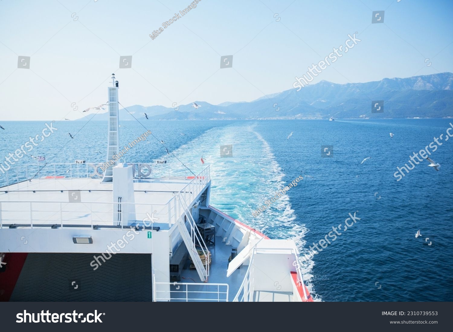 Summer seascape with seagulls flying around ferry. Sea water waves trails from ferry boat. View from the ferries. Sunny clear blue sky. Mountain landscape of Thassos, Greece.	 #2310739553