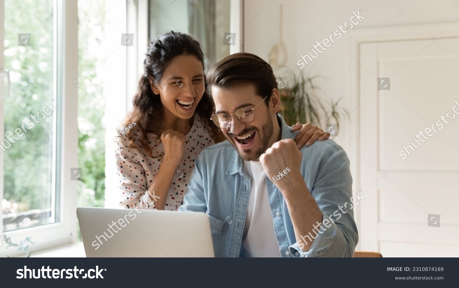 Overjoyed loving young bonding family couple looking at computer screen, getting email with amazing good news, celebrating online lottery betting gambling giveaway win, internet success concept. #2310874169