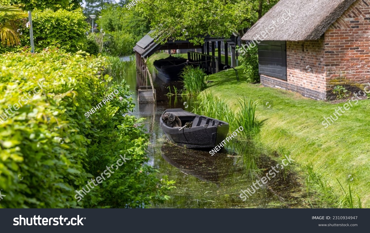 Small black wooden fishing boat in the canal at Giethoorn, Netherlands. #2310934947
