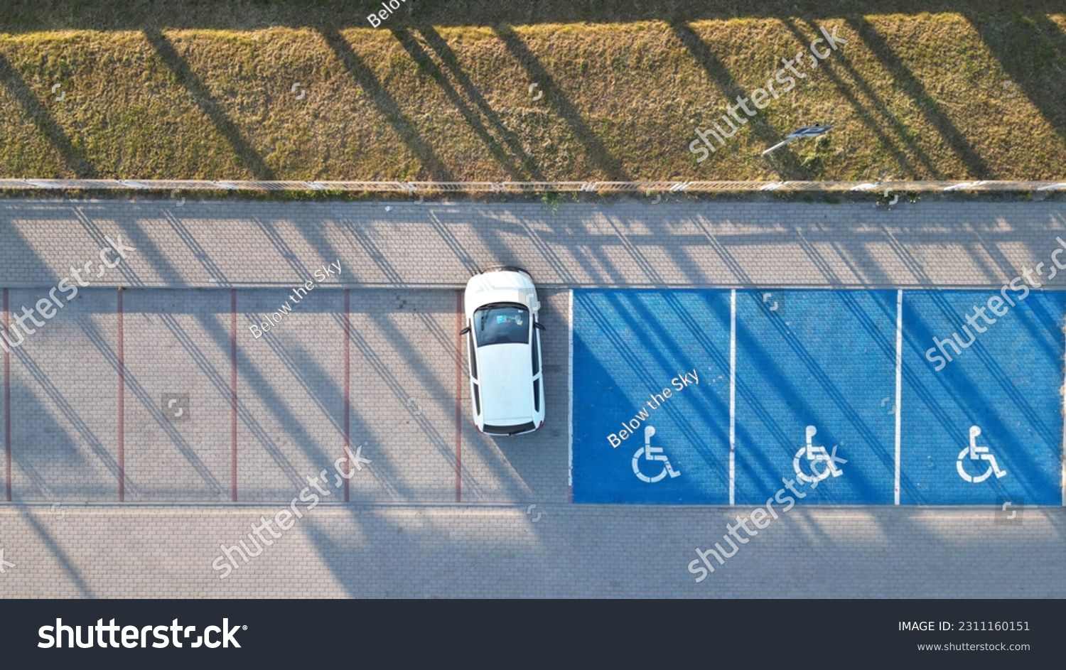 Outdoor car parking with handicapped symbol icon close to railway station.. Parking places reserved for disabled person. Aerial drone view. #2311160151
