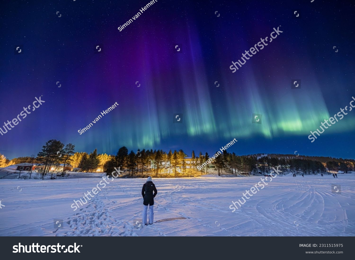 Young girl watching purple, blue and green Northern lights (aurora borealis) 
above Ounasjärvi lake in Hetta, Lapland, Finland #2311515975