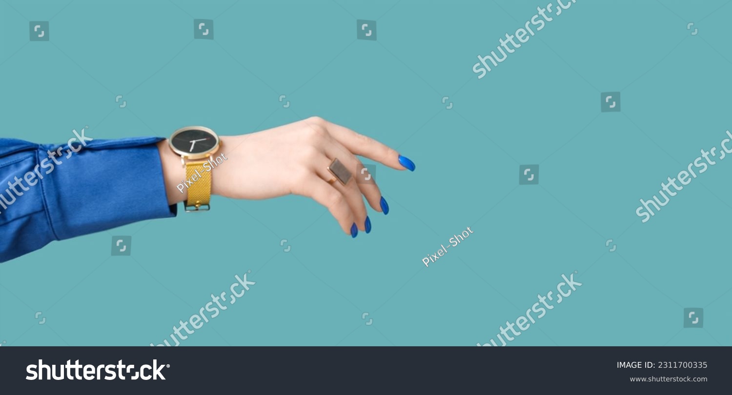 Female hand with golden wristwatch on blue background with space for text #2311700335