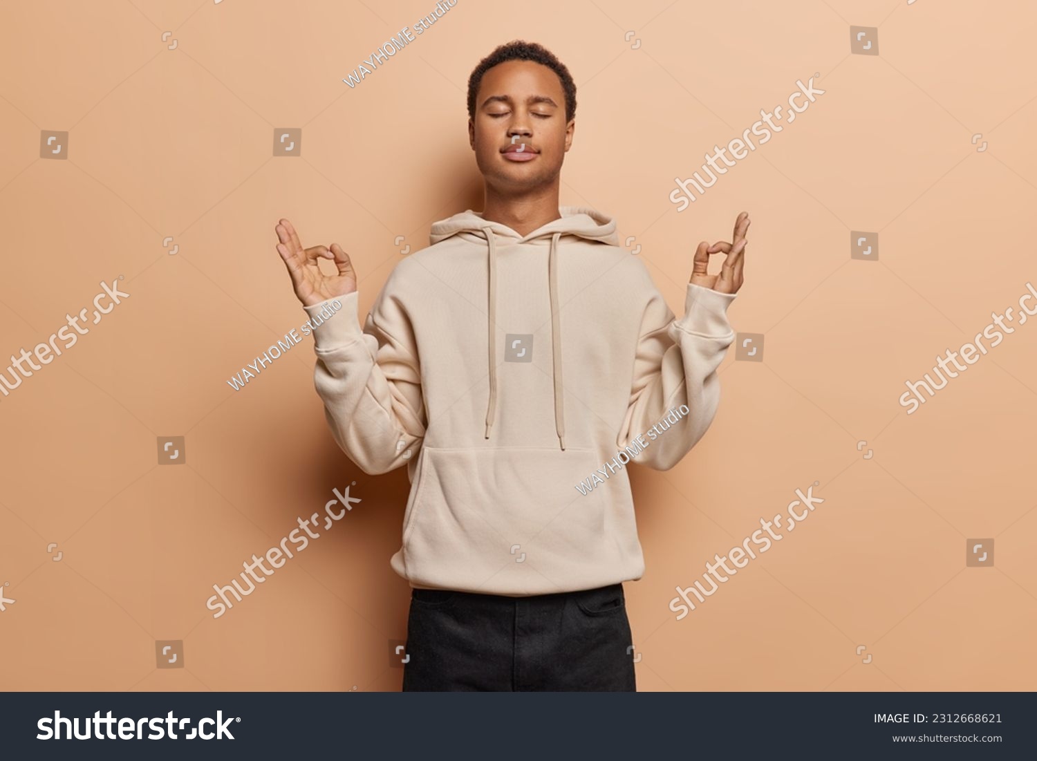 Tranquil young man exudes sense of calmness as peacefully closes his eyes practices mindful breathing and yoga captures essence of inner peace and relaxation dressed casually isolated over brown wall #2312668621
