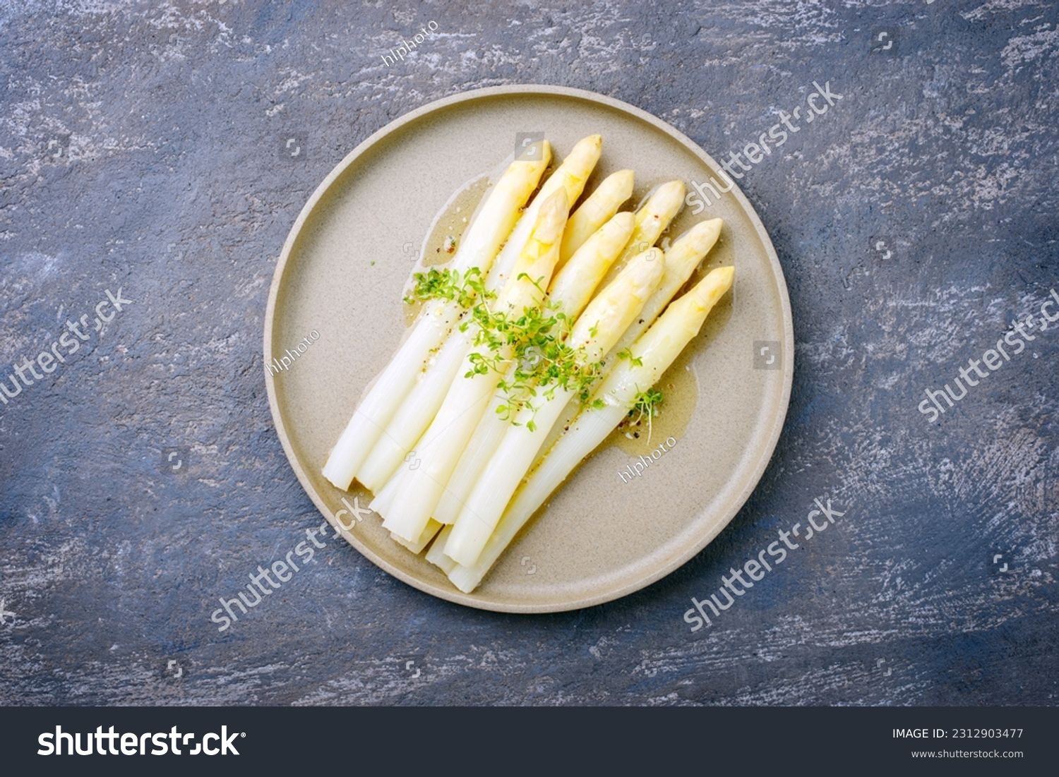 Modern style traditional steamed white asparagus with butter sauce hollandaise and cress served as top view on a Nordic design plate with copy space #2312903477