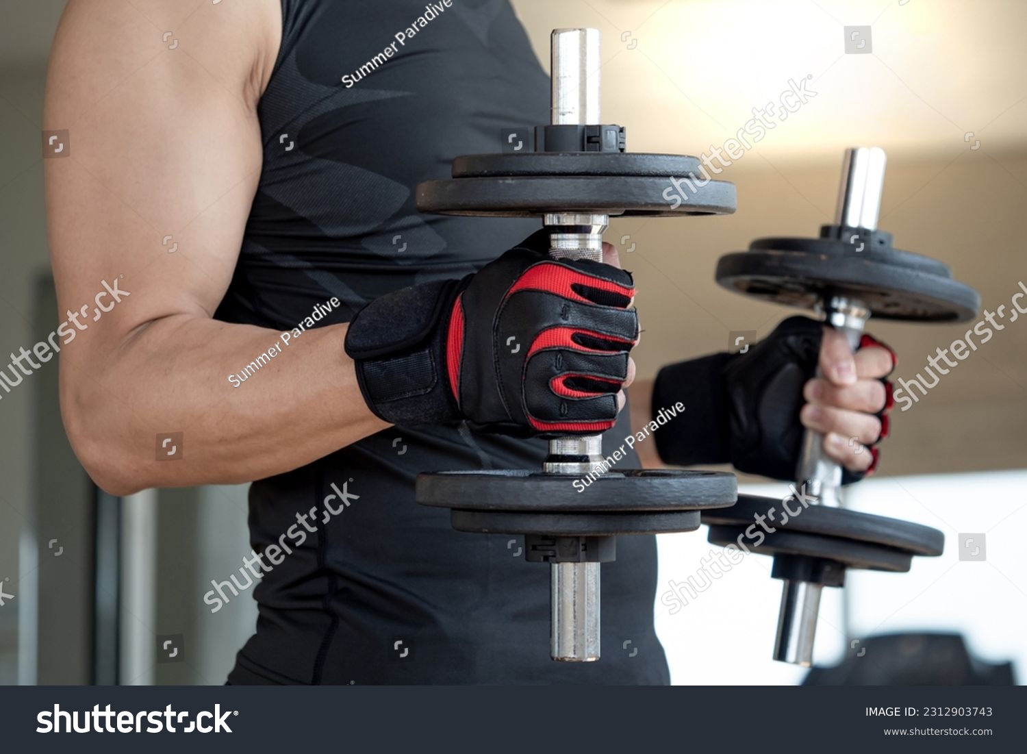 Sport man with well trained body in black sportswear wearing sport gloves lifting two dumbbells in fitness gym. Weight training and bodybuilding workout concept #2312903743