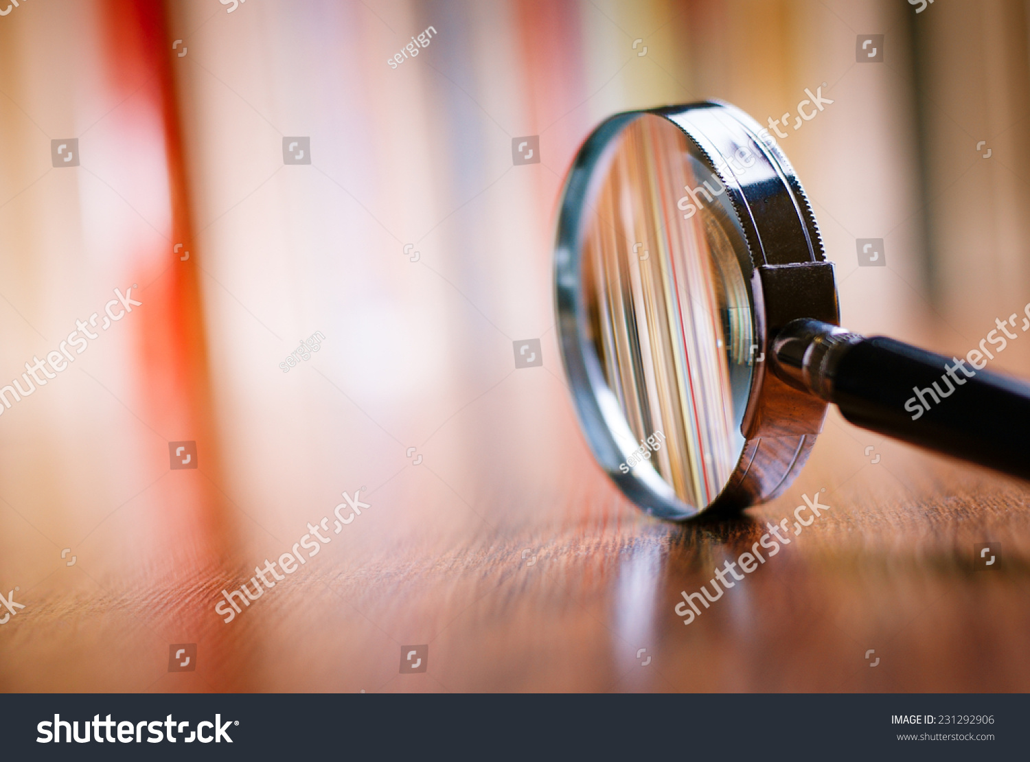 Close up Single Magnifying Glass with Black Handle, Leaning on the Wooden Table at the Office. #231292906