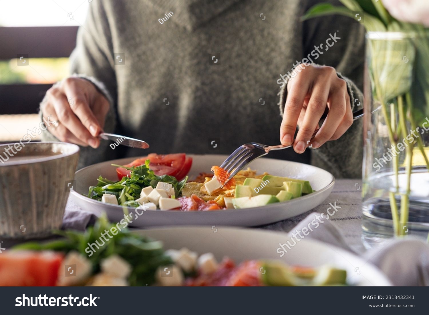 Woman eating healthy morning meal. Healthy breakfast with salmon, omelet, avocado, fresh herbs, cheese and tomatoes #2313432341