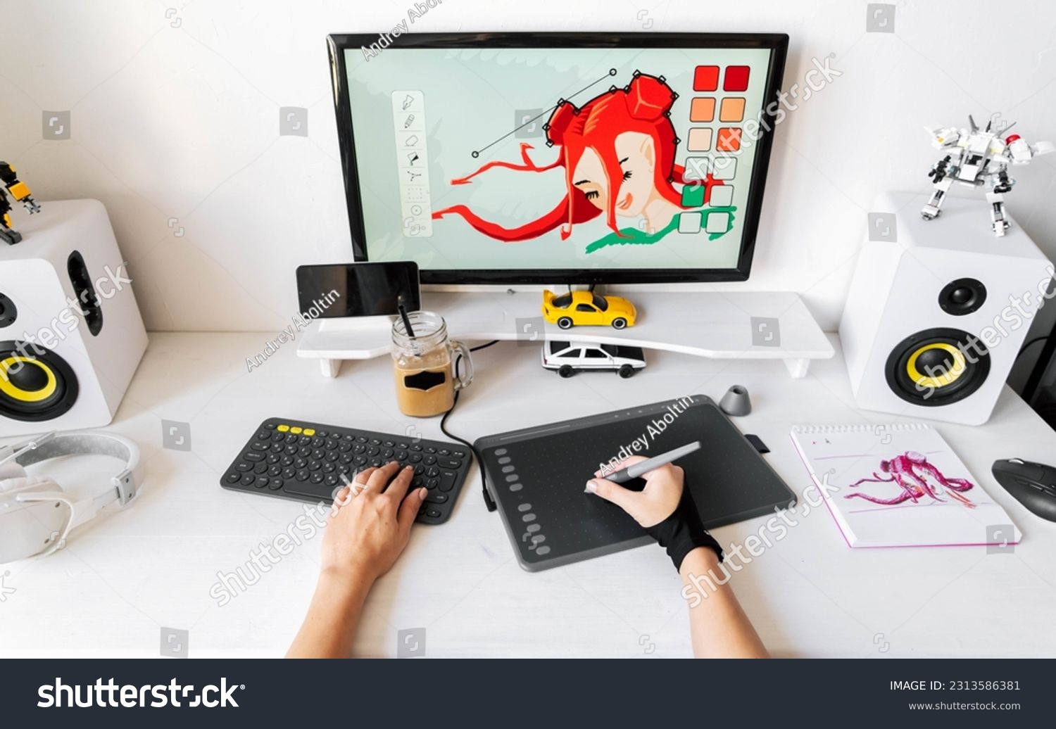 A young girl profession digital artist draws on a PC using a graphics tablet in her comfortable home office. #2313586381