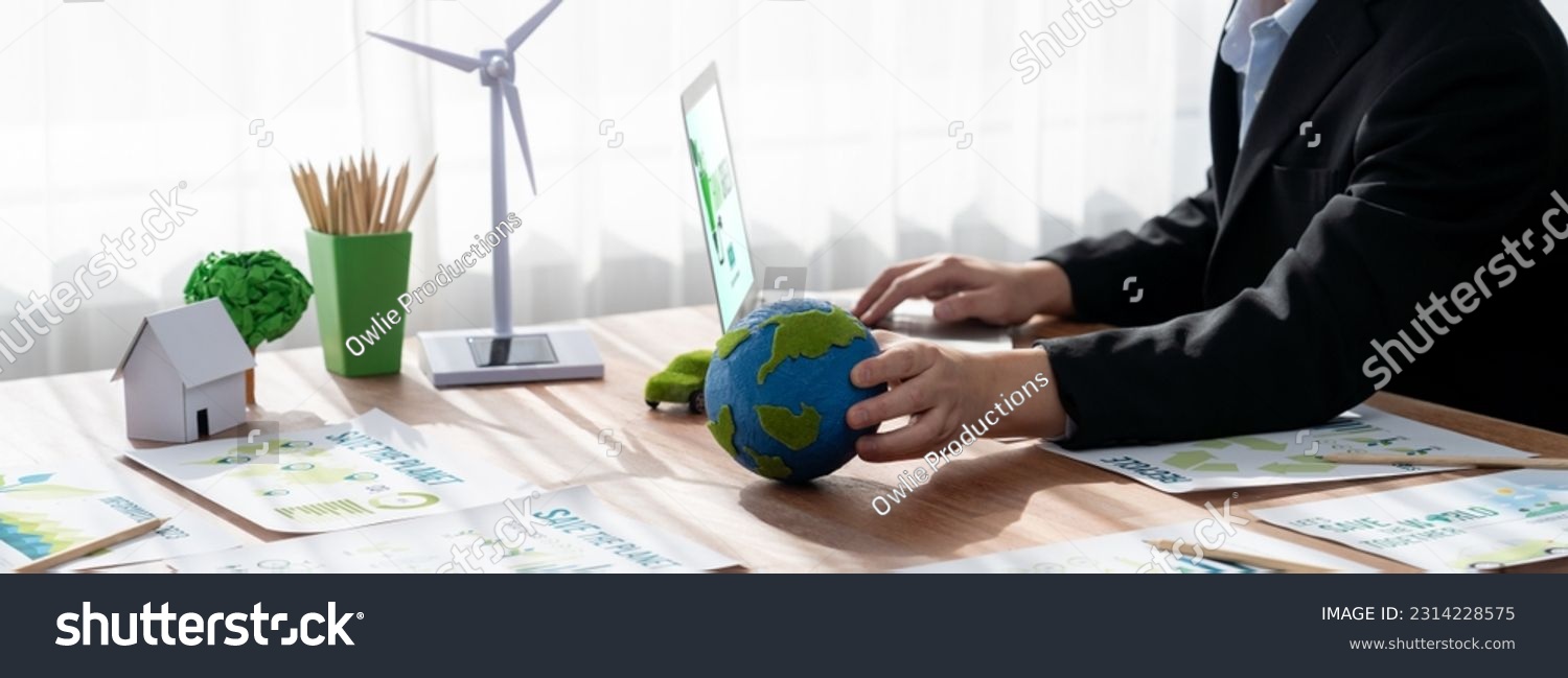 Businessman or CEO of the green corporate company holding paper Earth as concept for environmental friendly business to reduce CO2 emission and carbon footprint for cleann ecology. Trailblazing #2314228575