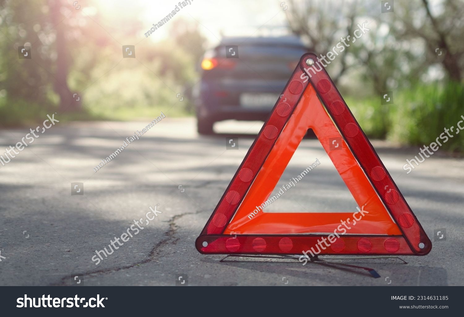 The warning triangle is at the back of the car at a safe distance.Car on the road behind warning triangle.The triangle placed behind the car. #2314631185