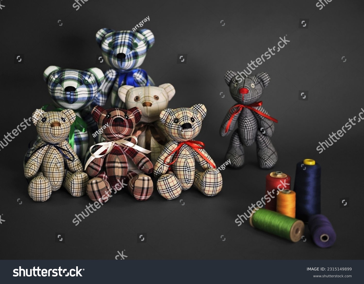 Teddy bears. Children's handmade soft toys. Sewn bears in cage. Several bears and threads on dark gray surface. Front view. Dark gray background. High quality photo #2315149899