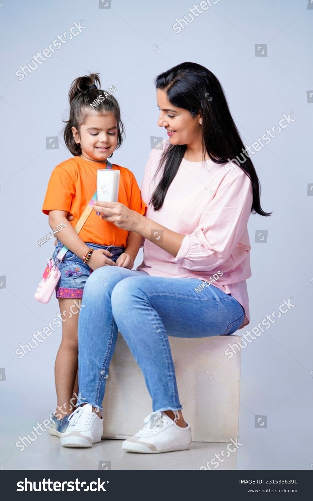 Indian mother giving milk in glass his daughter on white background. #2315356391