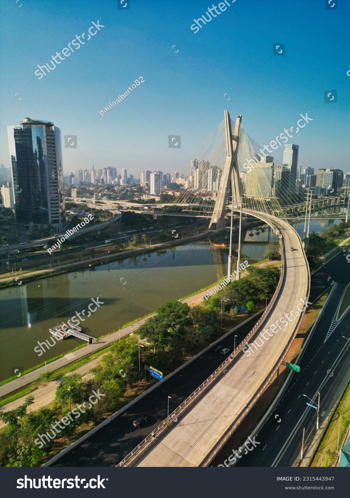 2023 view of the Pinheiros river with modern buildings beside it and the famous Octavio Frias de Oliveira bridge in the city of São Paulo. #2315443947