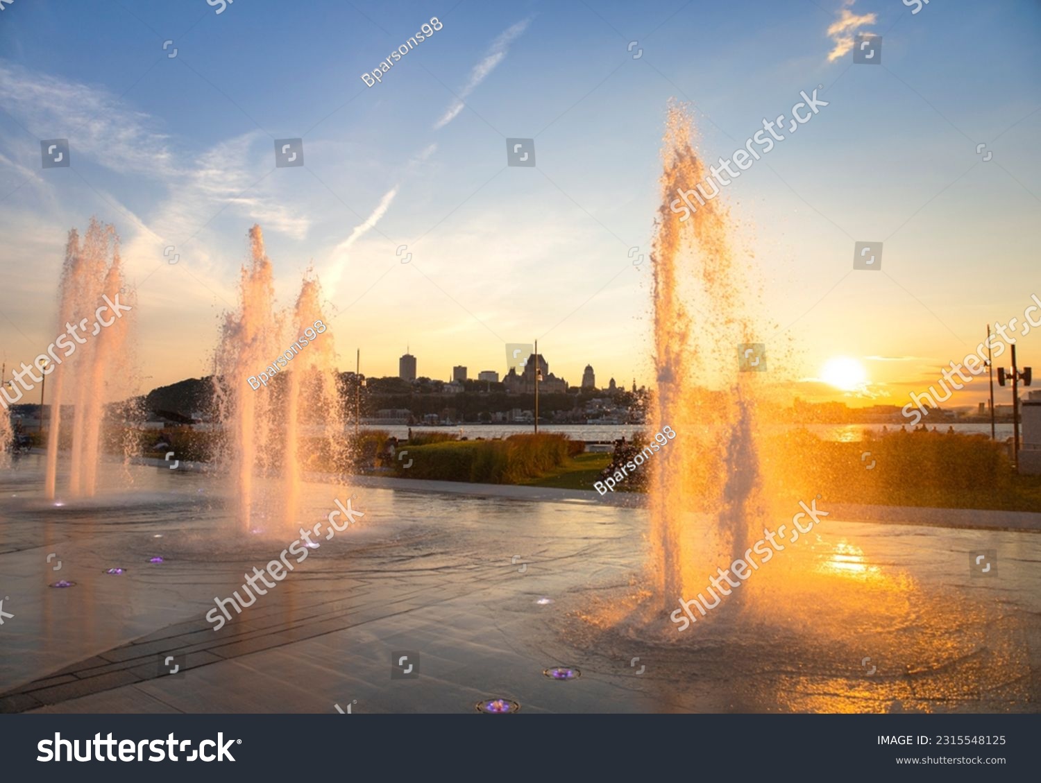 Water fountains backlit by an orange sunset #2315548125