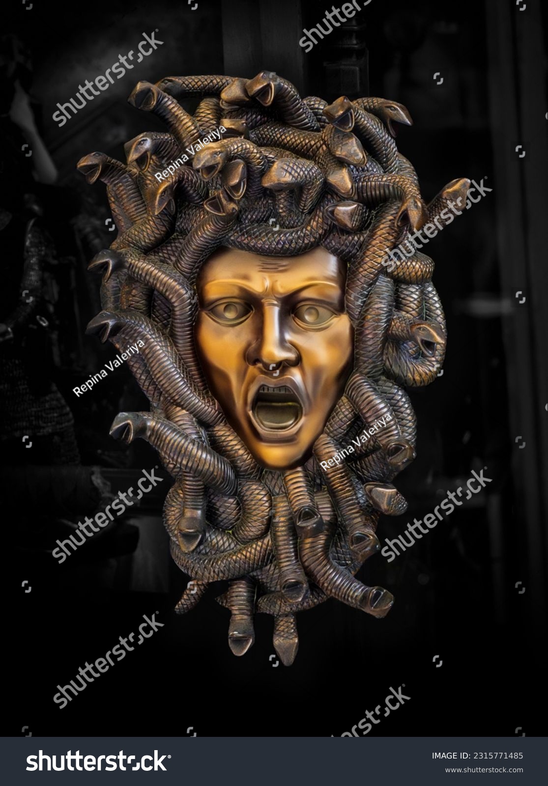 Metal mask of the Medusa Gorgon with framing snakes around the face, horrible creature from Greek mythology in european antique culture. Head of Medusa at a street souvenir market in Rhodes, Greece. #2315771485