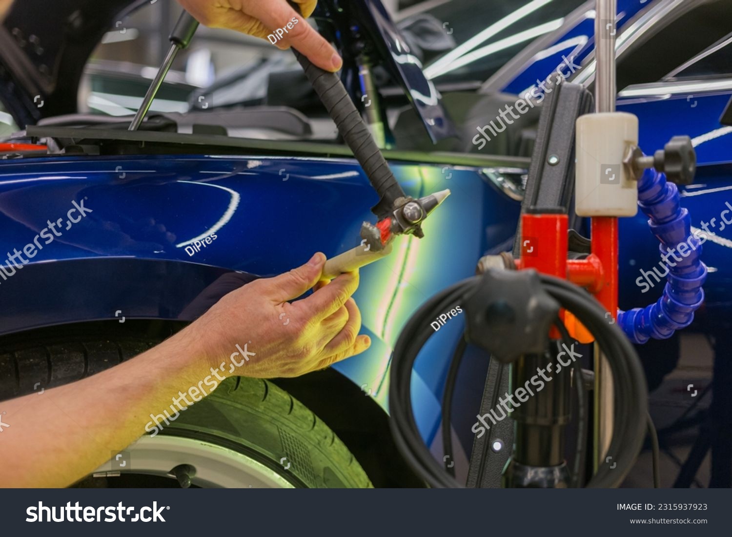 Removal of dents without painting. PDR technology for car body repair. PDR. The mechanic at the auto shop with tools to repair dents in car body. Body repair. #2315937923