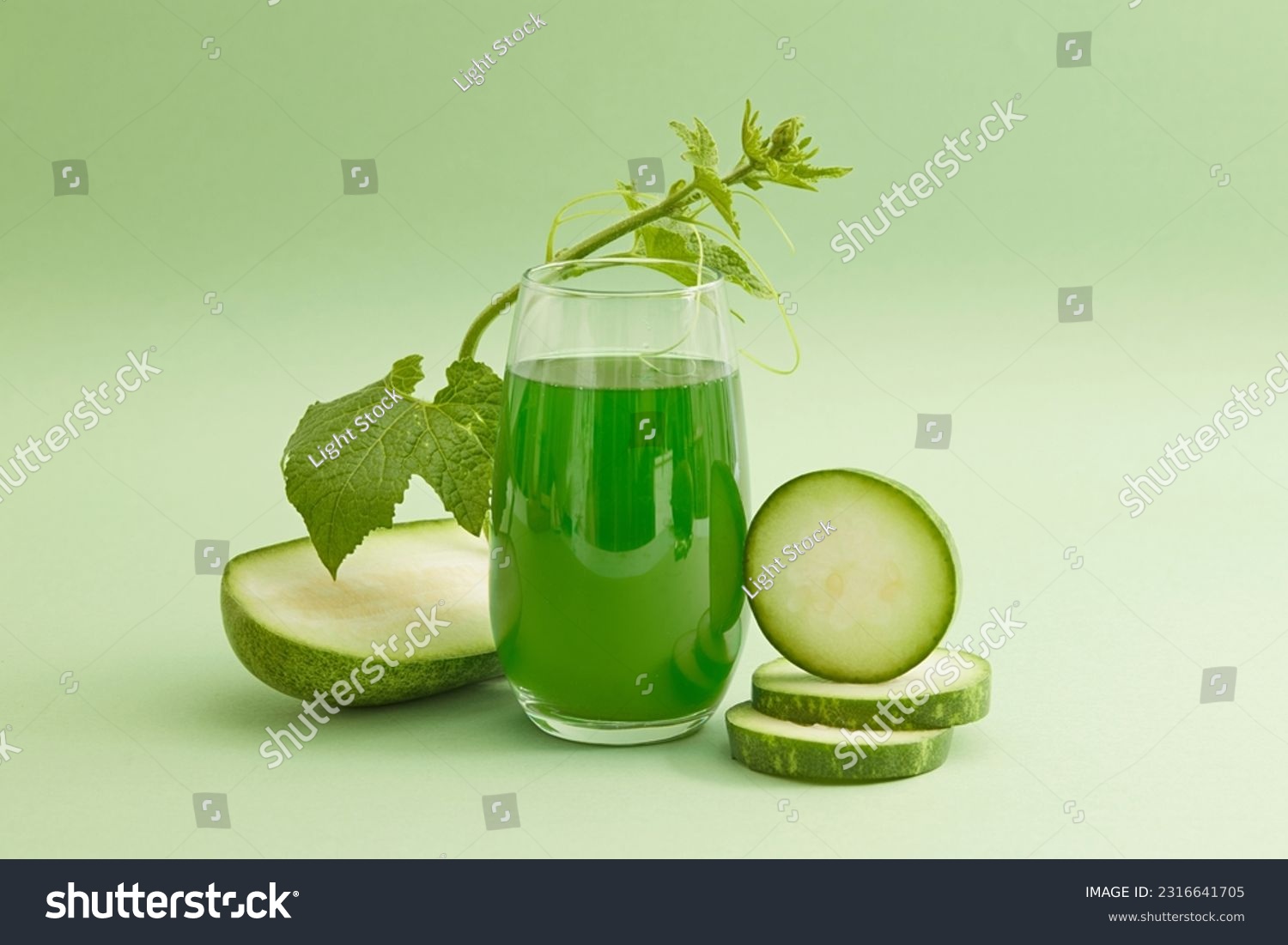 Front view of a glass of juice with fresh winter melon slices and leaf decorated on a light green background. Drinking winter melon tea regularly helps cool the body very well on hot days. #2316641705