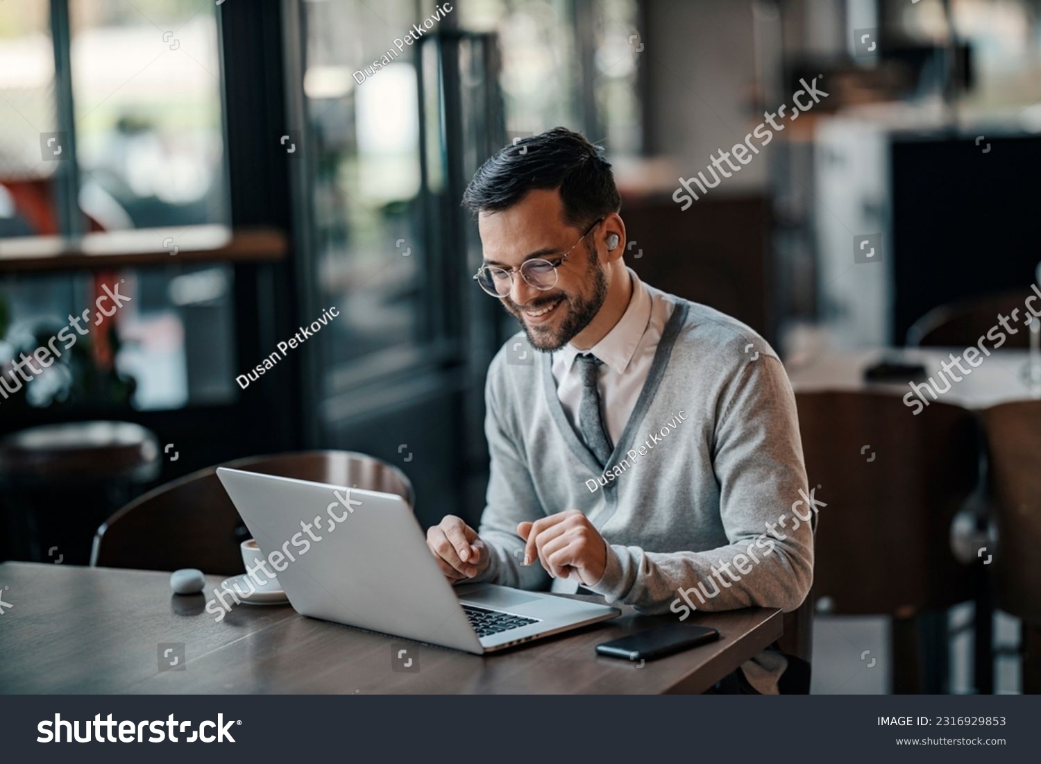 A young trendy businessman is using his laptop in a coffee shop. #2316929853