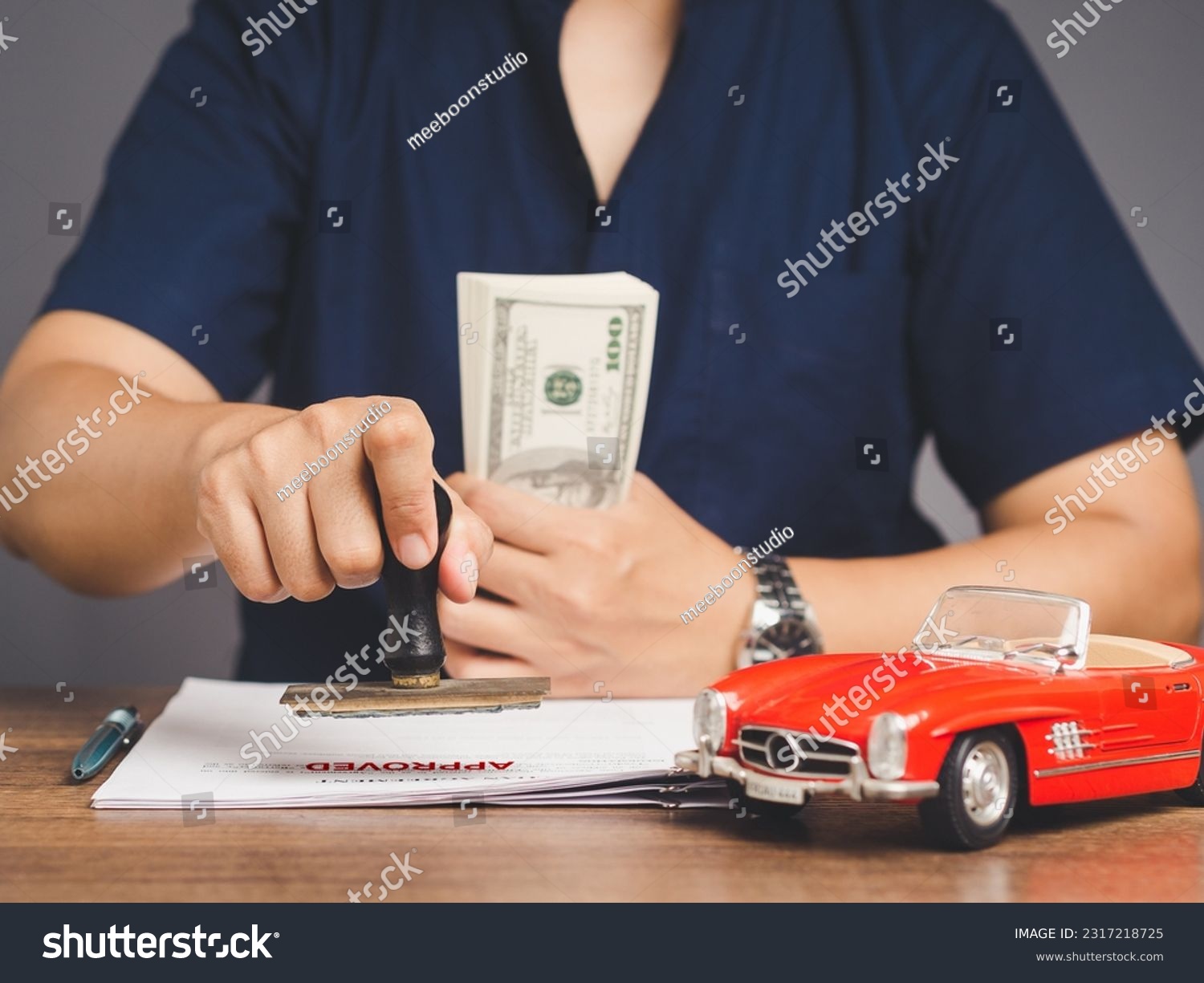 Car loan or Title loan. Businessman stamped the approved for car loan agreement while sitting at the table in the office. #2317218725