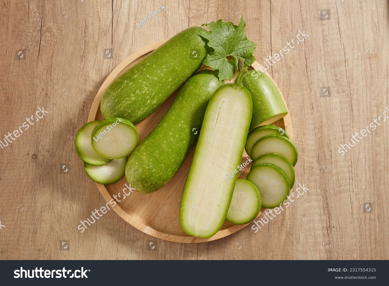 Top view of a wooden tray in round-shaped containing many round slices of winter melon. Winter melon (Benincasa hispida) is rich in vitamin C and antioxidants that improve skin health #2317554315