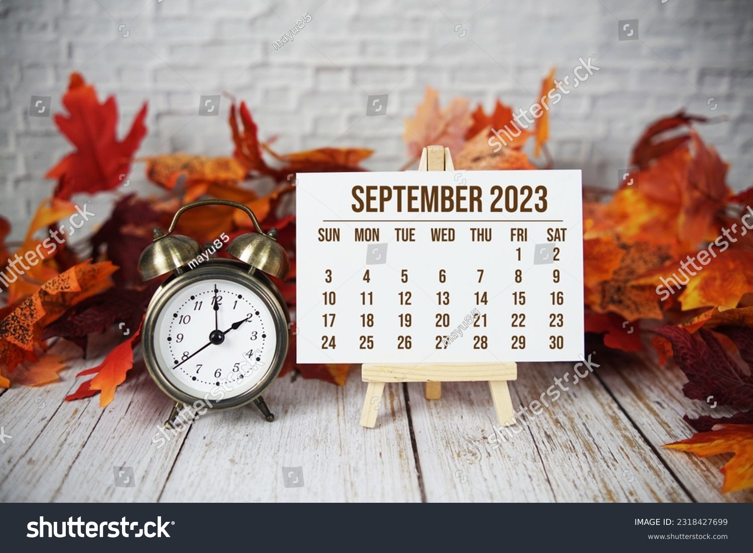 September 2023 monthly calendar with maple leaf on wooden background #2318427699