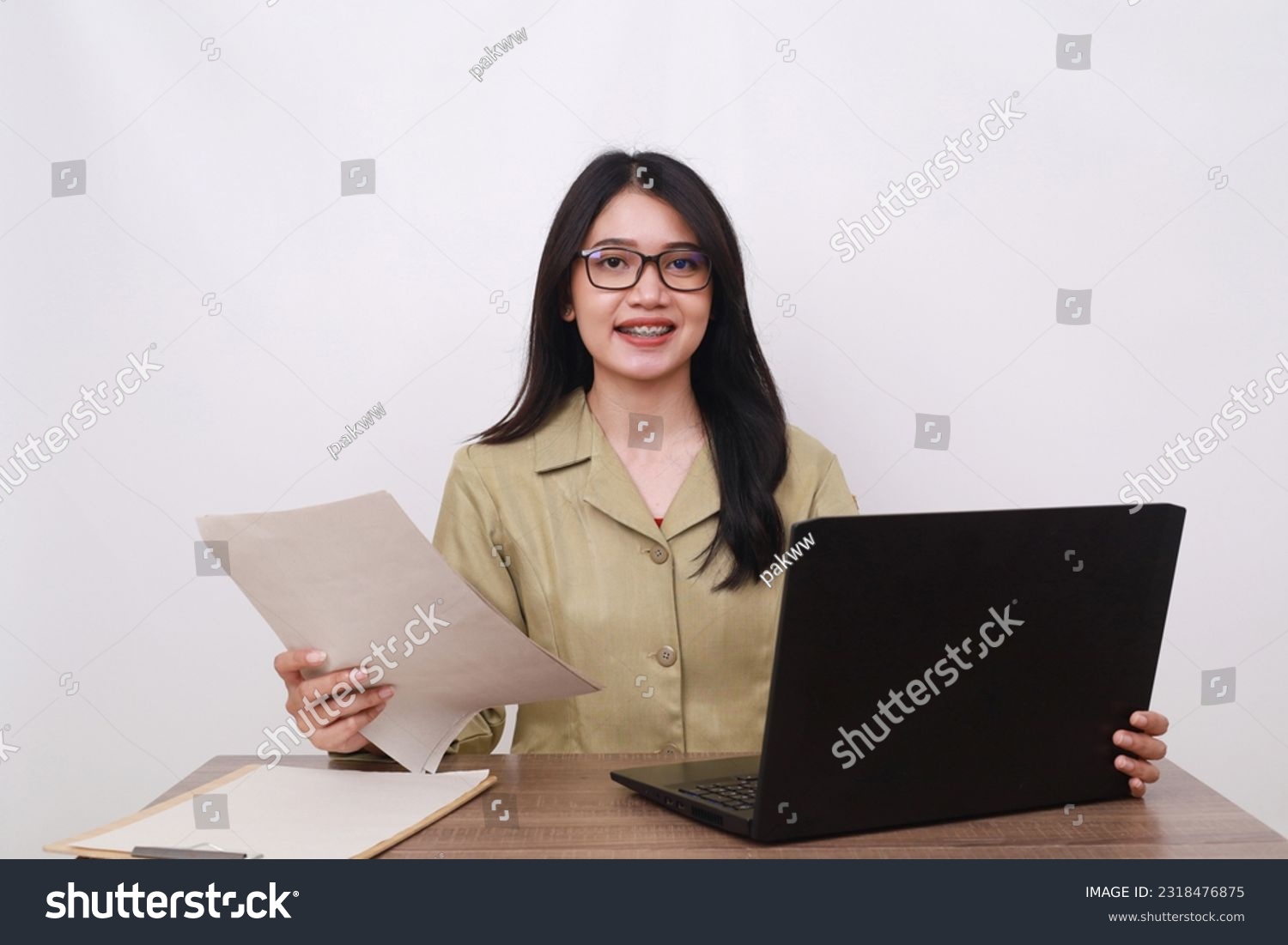 Female teacher in civil servant uniform with paper and laptop on the desk #2318476875