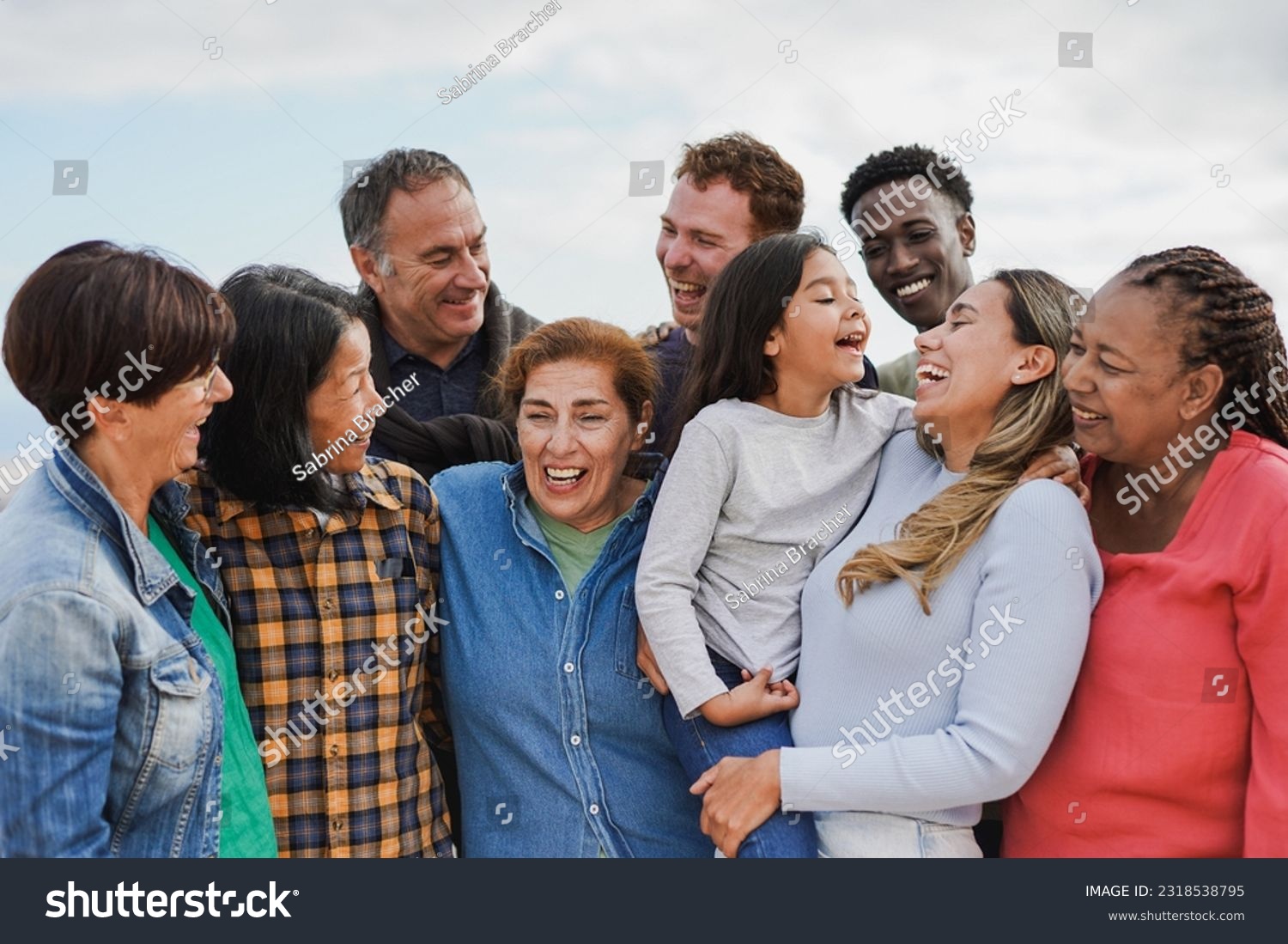 Crowd of multi generational people hugging each other outdoor - Multiracial friends having fun together #2318538795