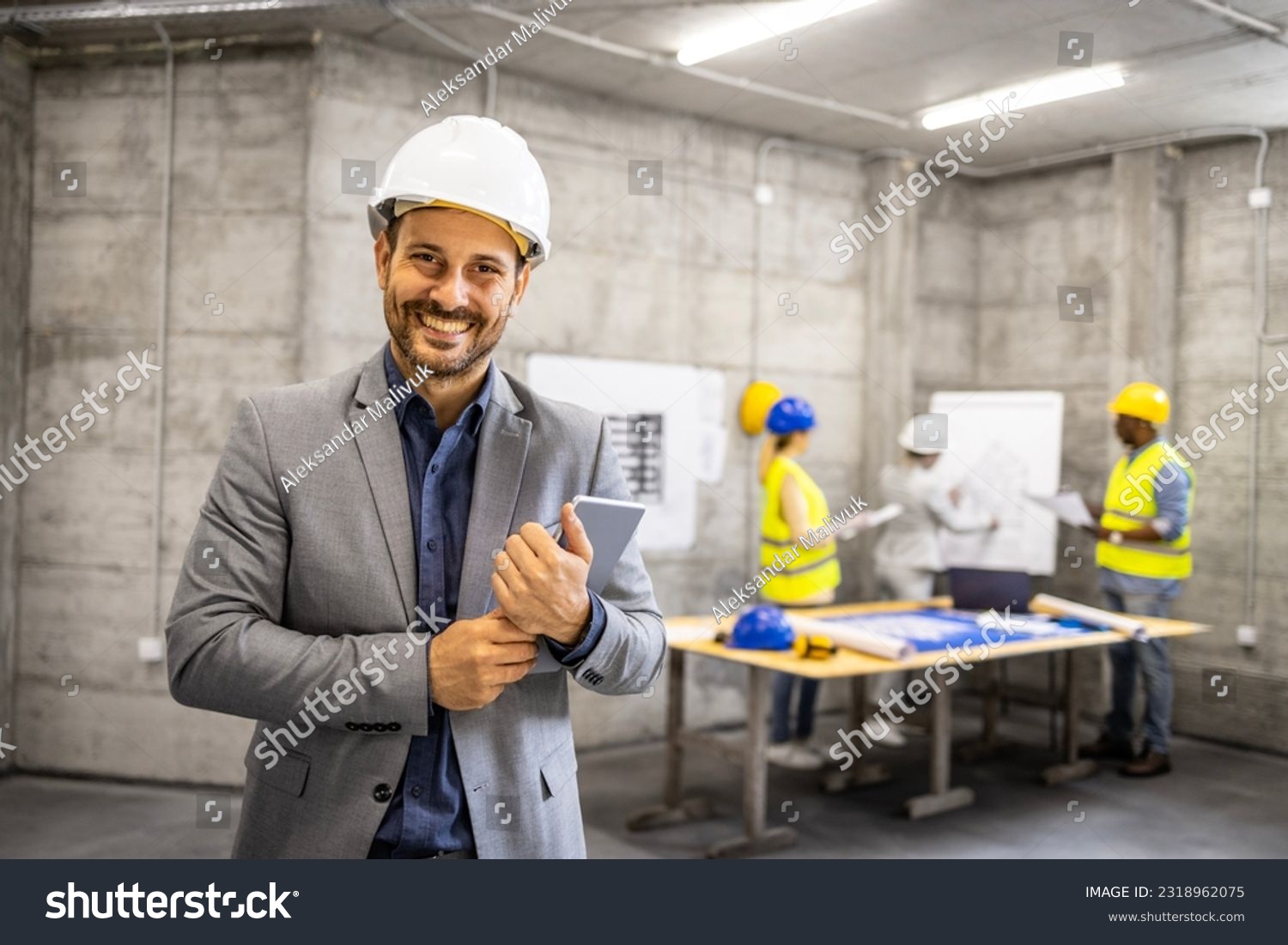 Portrait of structural engineer in business suit and hardhat holding tablet computer at construction site. #2318962075
