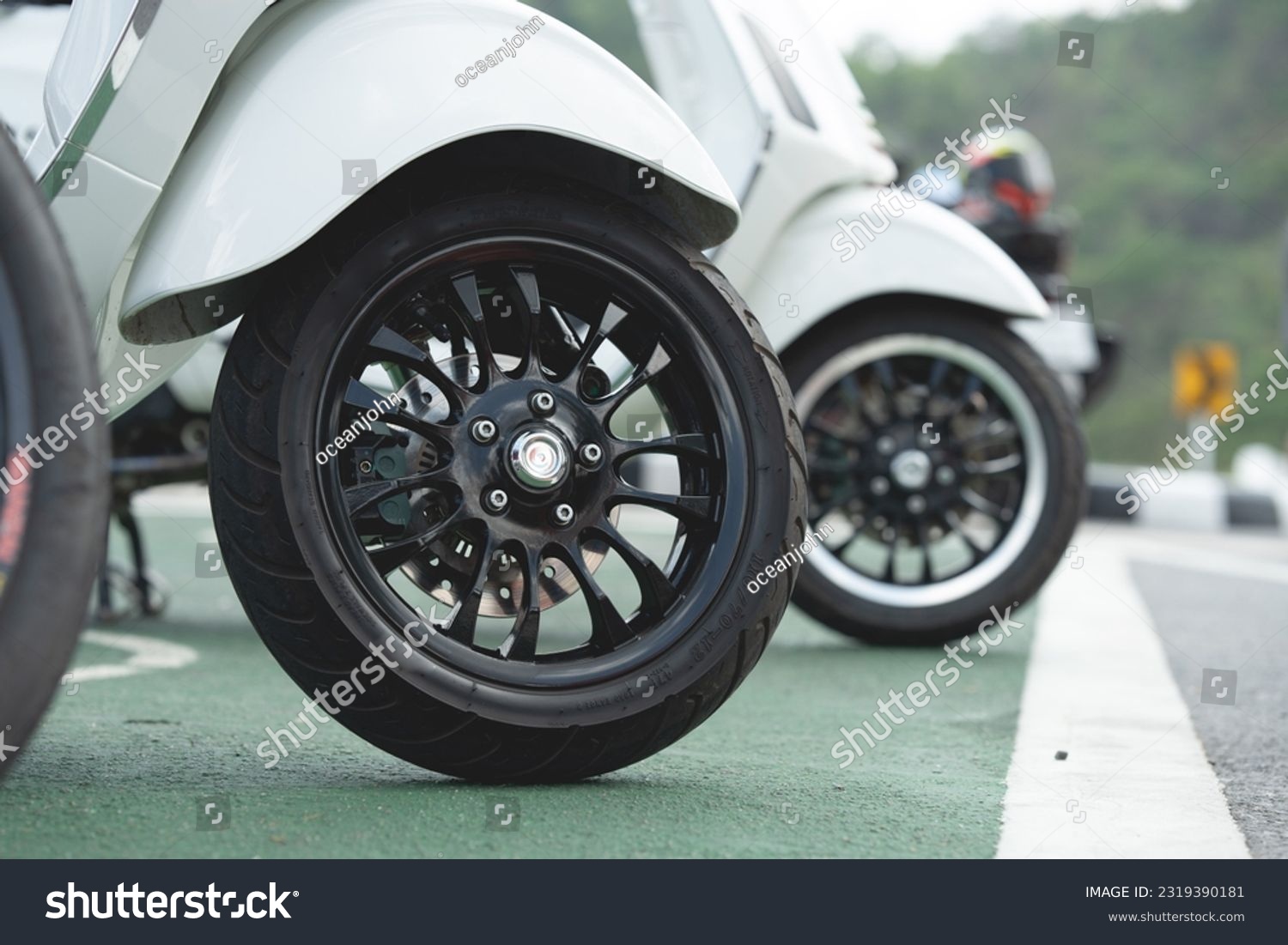 Close-up of wheels of a scooter motorcycle parked on a beautiful road in the daytime.	 #2319390181