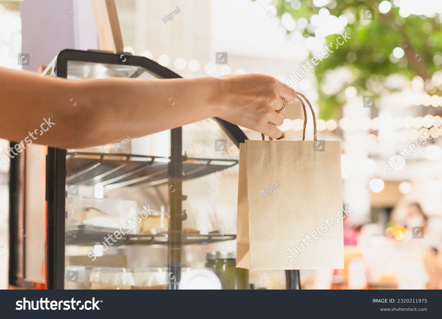 Waitress at counter giving eco friendly paper bag in cafe #2320211975