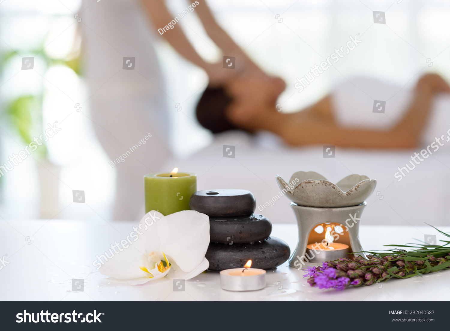 Spa concept: zen stones, candles and flowers on the background of woman receiving treatment #232040587