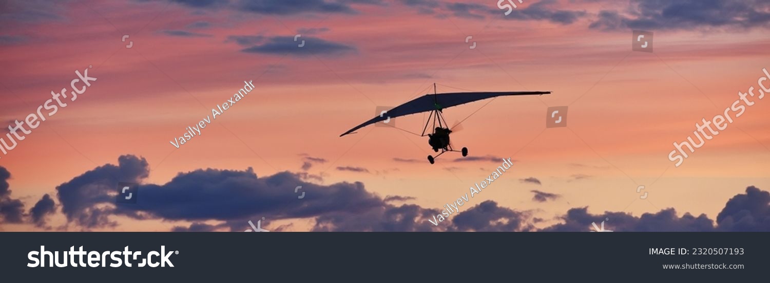 Hang glider on a motor on a summer evening against the backdrop of a sunset sky. Extreme sport. Banner, blank for an advertising layout with a place for writing #2320507193