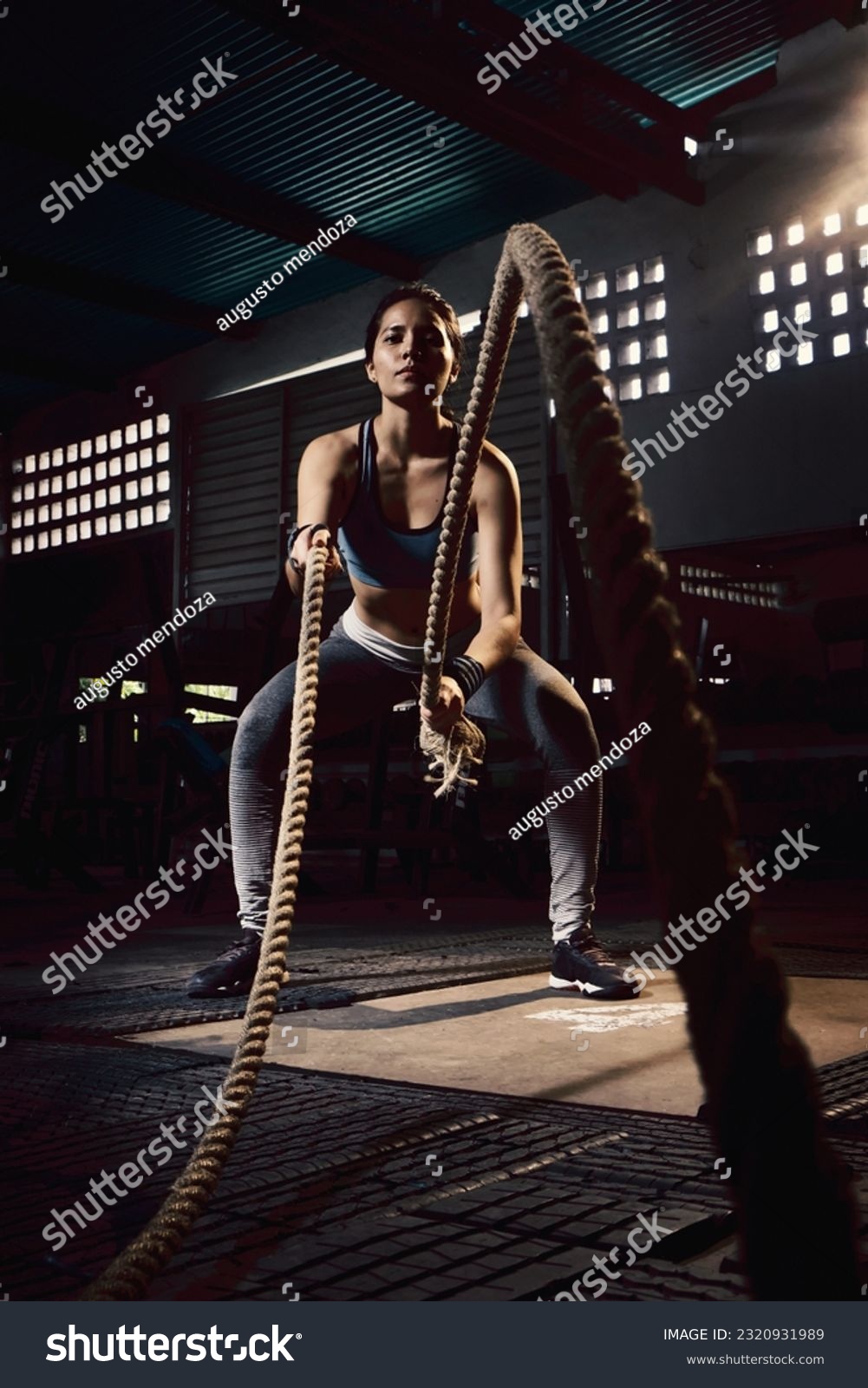 Woman training with battle rope in cross-training gym #2320931989