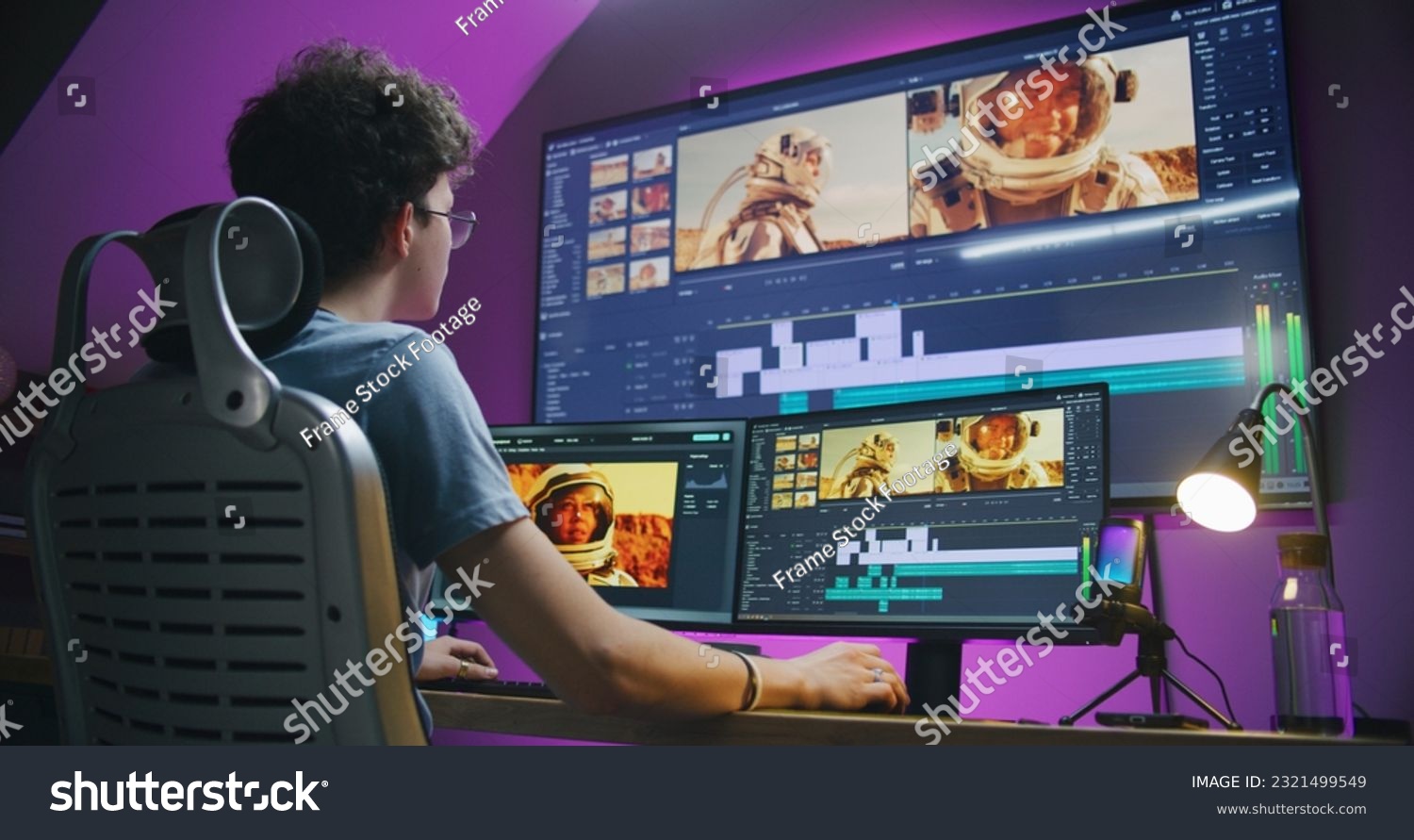 Young editor, video maker edits sound tracks for movie with astronauts, works at home office. Film footage and program interface with tools on computer and big digital screen. Post production concept. #2321499549
