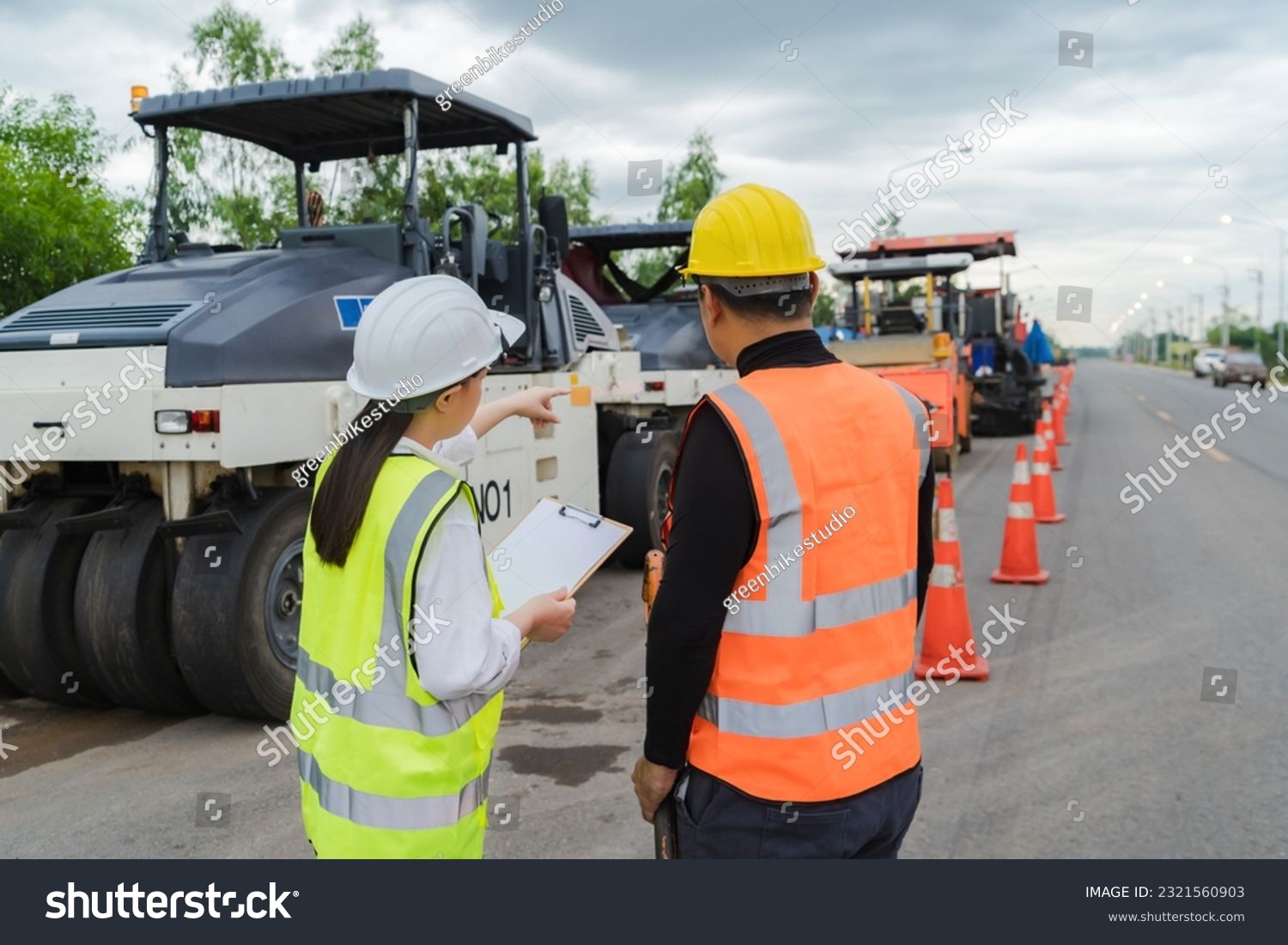 A female civil engineer consults with or with a contractor building a rural highway before commencing work to ensure completion. planning cooperation concept #2321560903
