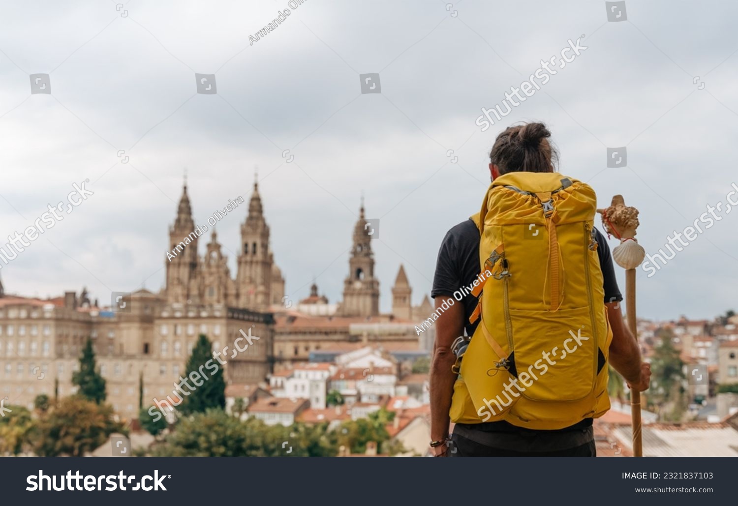 Camino de Santiago - Young hipster pilgrim ends the Way of St James pilgrimage enjoying cathedral and the Santiago de Compostela old town cityscape in Galicia, Spain #2321837103