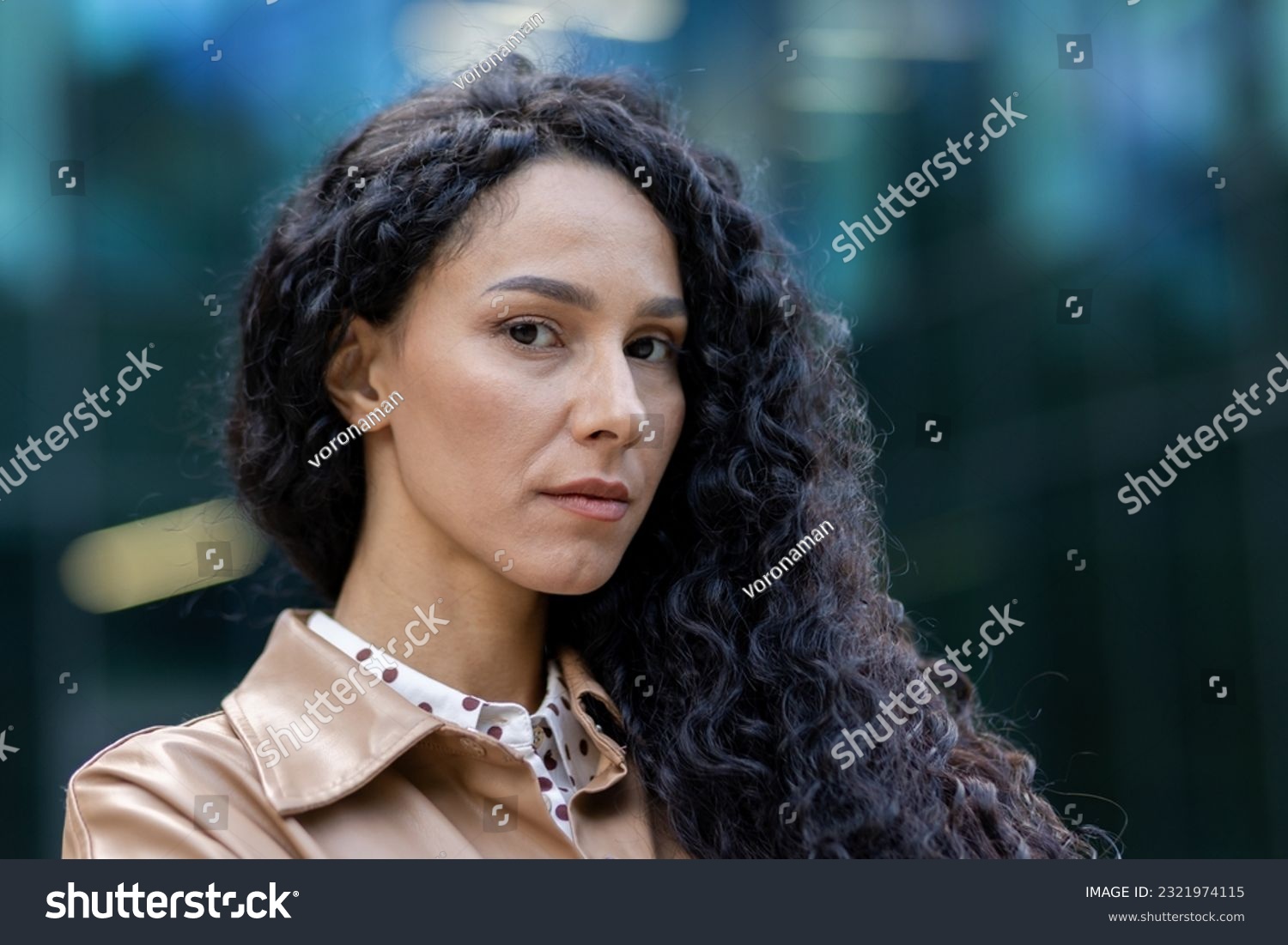 Portrait of mature adult business woman outside office building, close up Latin American woman with curly hair looking at camera, woman boss financier in business clothes. #2321974115