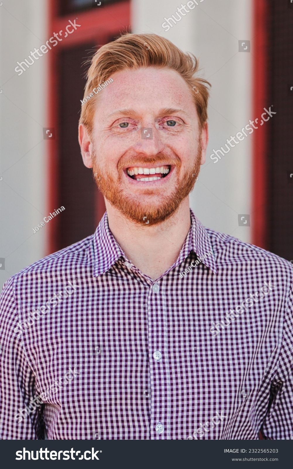 Vertical individual portrait of a formal joyful redhead formal guy standing outdoors smiling and looking at camera. Front view of positive young adult employee man laughing with friendly expression #2322565203