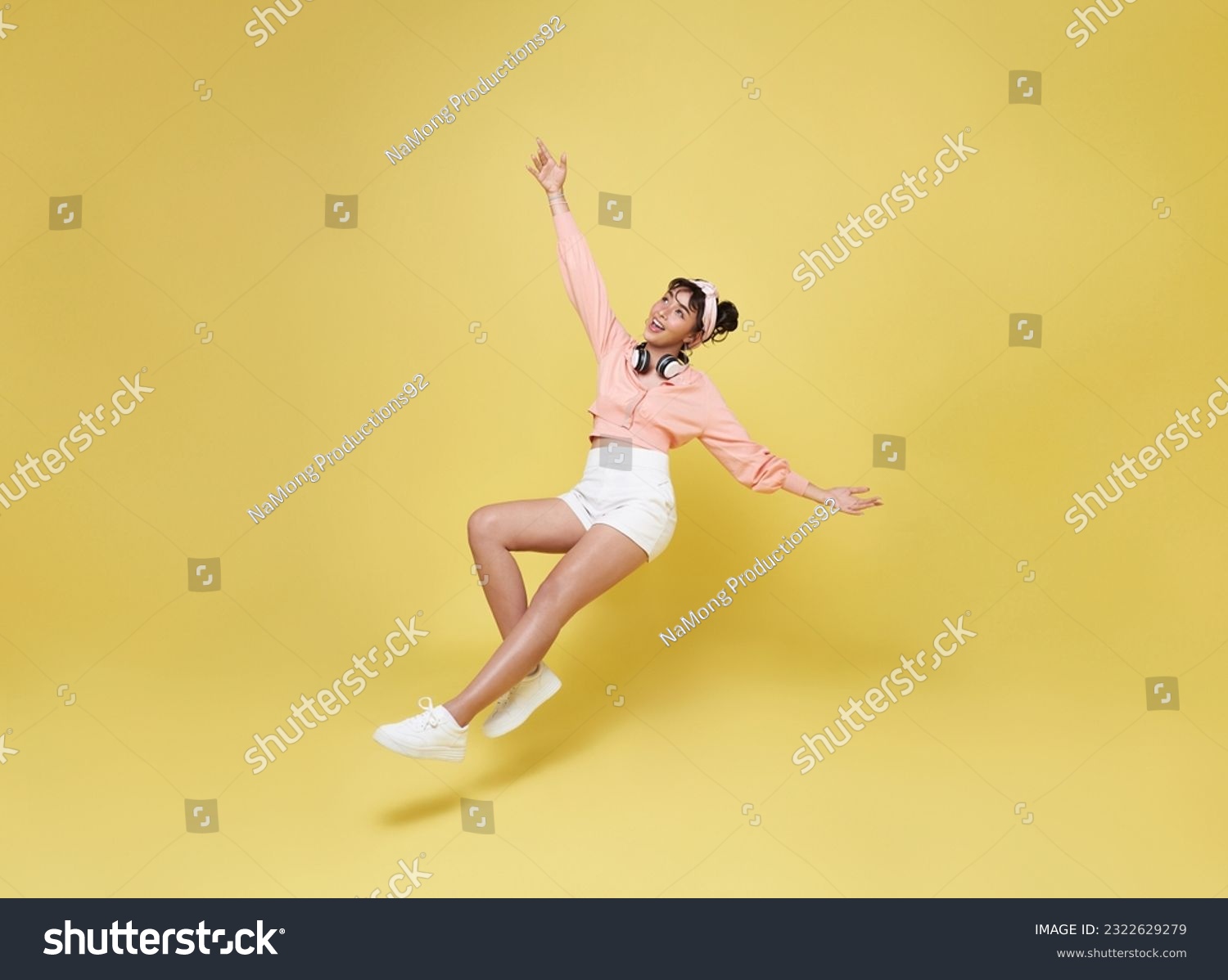 Happy smiling asian girl relaxing floating in mid-air isolated on yellow background. #2322629279
