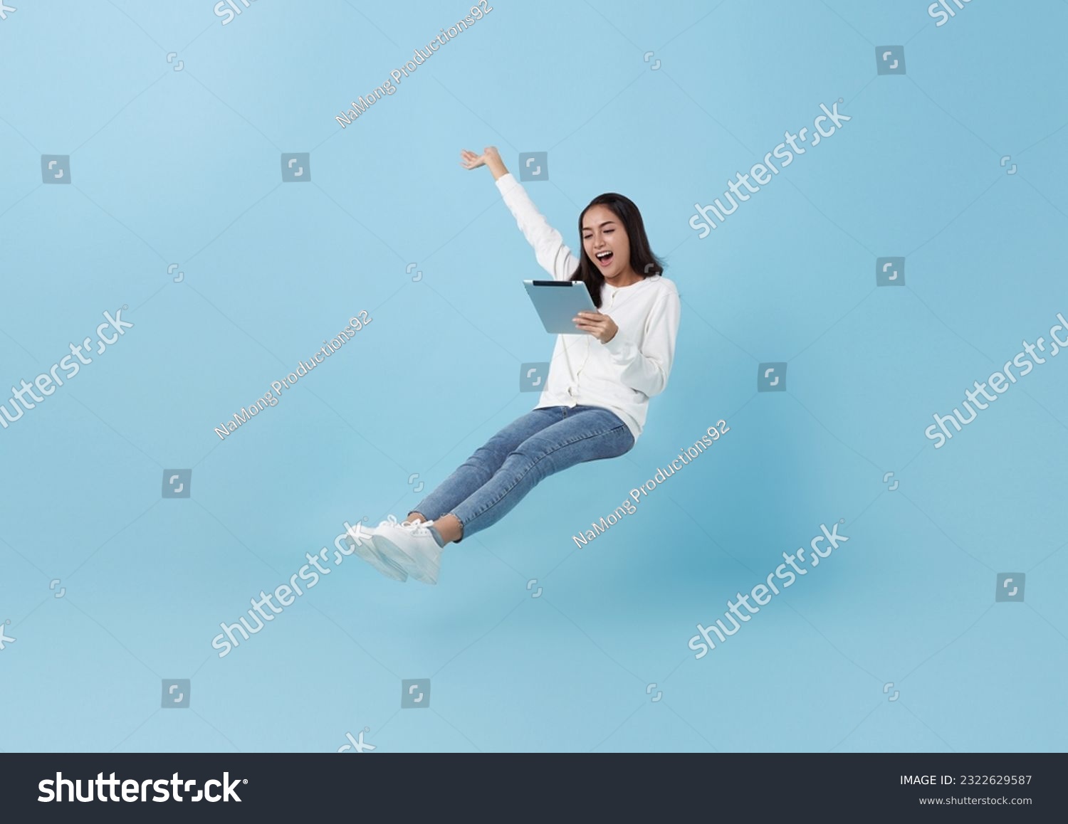 Happy asian teenage girl using tablet social media online floating in mid-air isolated on blue background. freedom fast internet technology concept. #2322629587