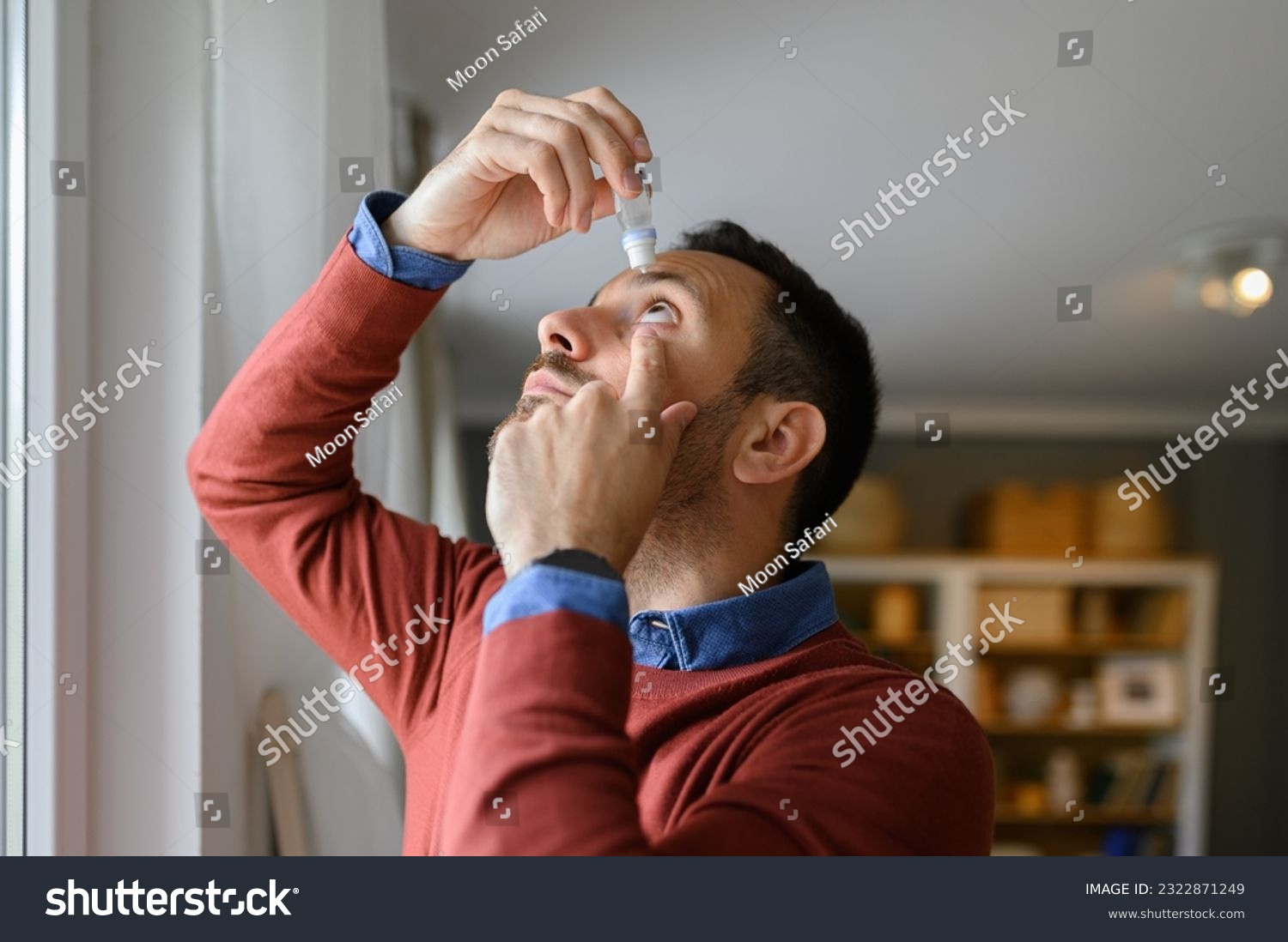 Close-up of young man applying eye drops to treat dry eye and irritation at home #2322871249
