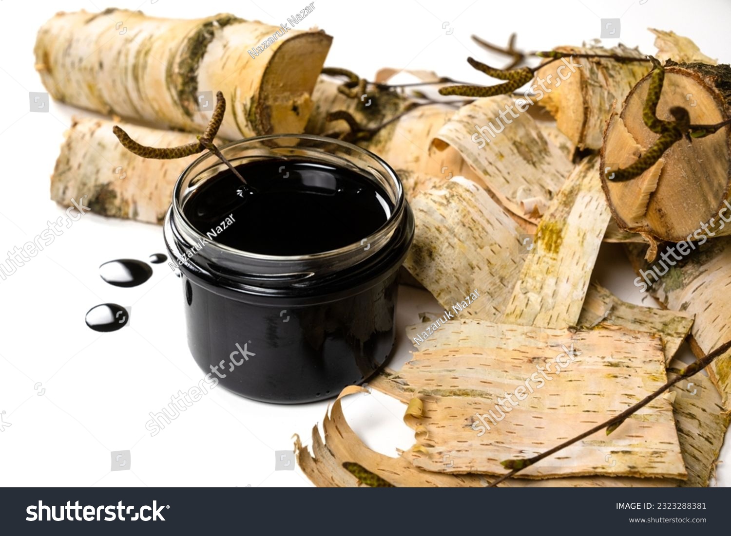 Birch tar or pitch in a jar and birch tree bark on white background. Wood tar. Liquid mineral tar from birch bark #2323288381