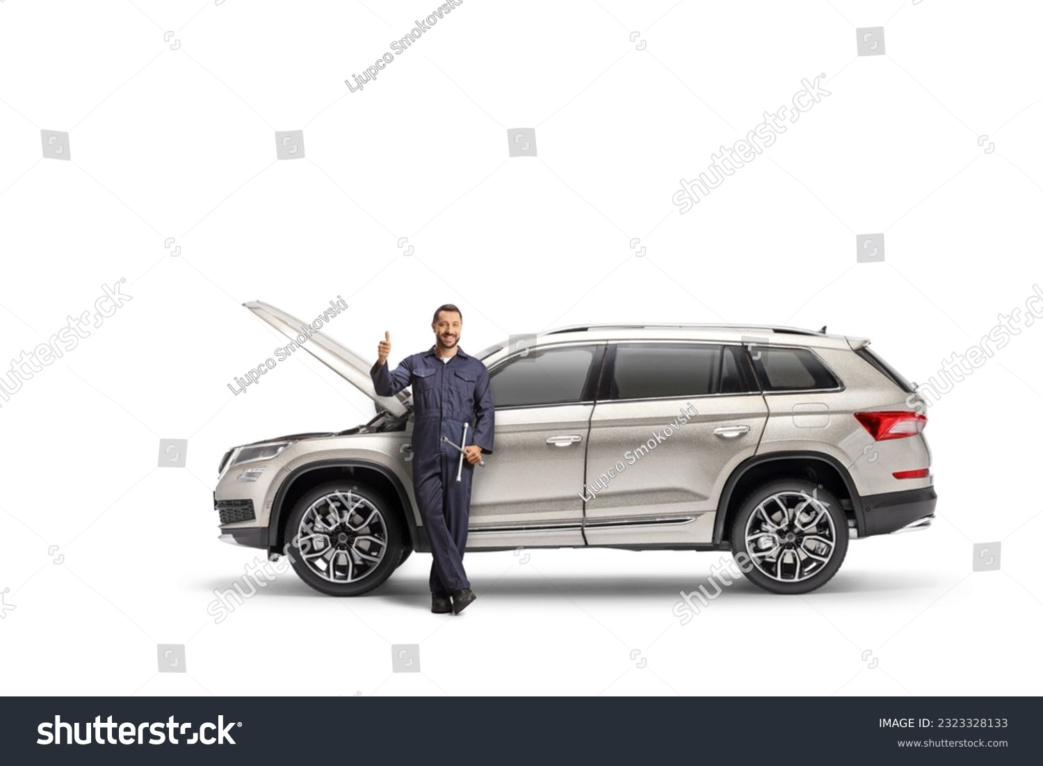 Auto mechanic leaning on a SUV with an open hood and gesturing thumbs up isolated on white background 

 #2323328133