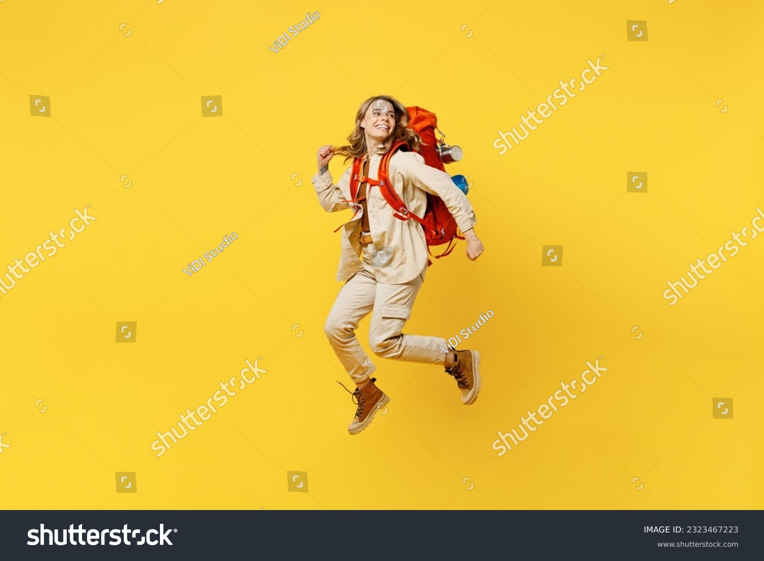 Full body young woman carry bag with stuff mat jump high look aside on area isolated on plain yellow background. Tourist leads active lifestyle walk on spare time. Hiking trek rest travel trip concept #2323467223